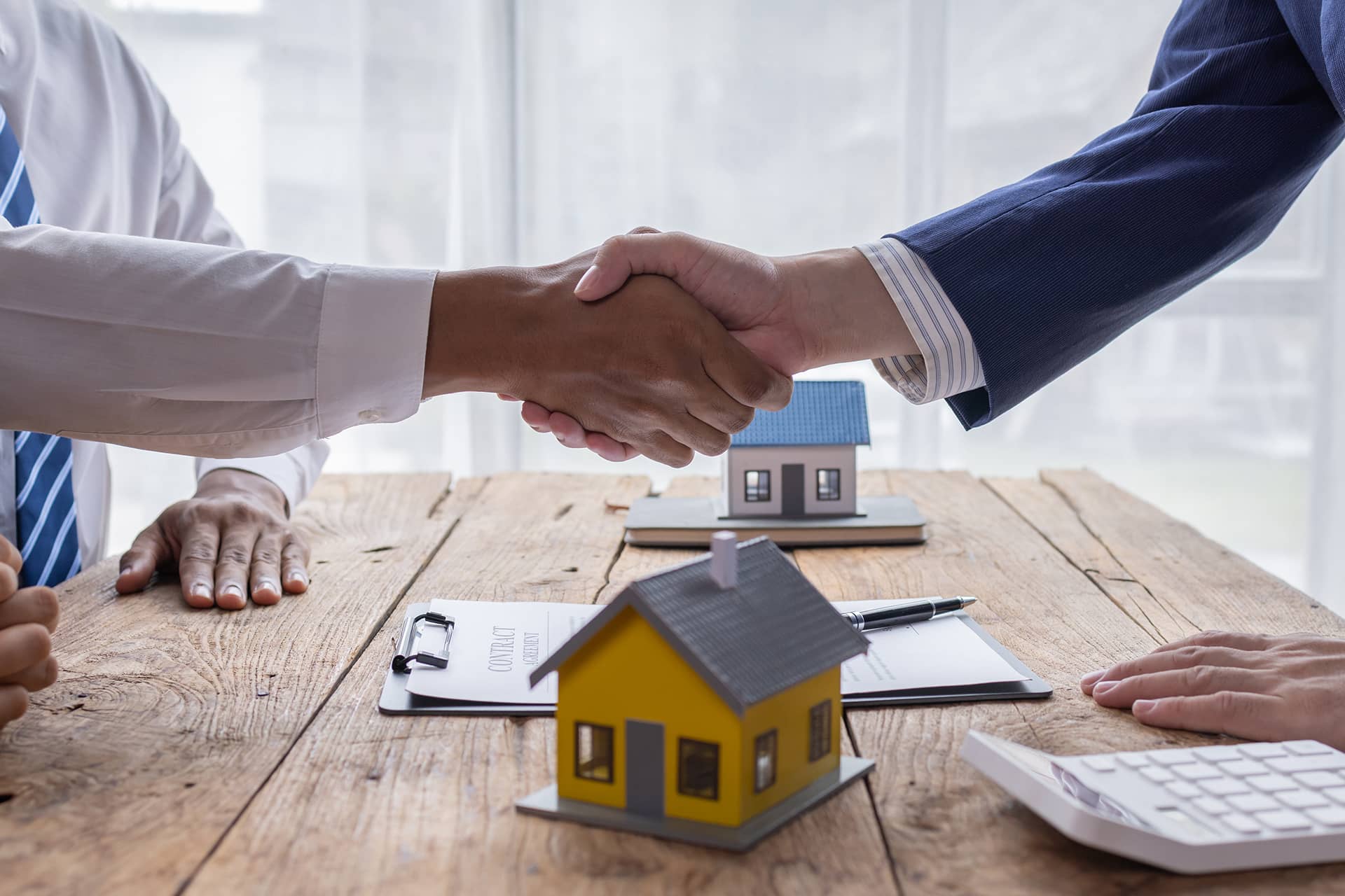 Handshake over rental agreement and house models for Chelton Brown letting agents in Northamptonshire.