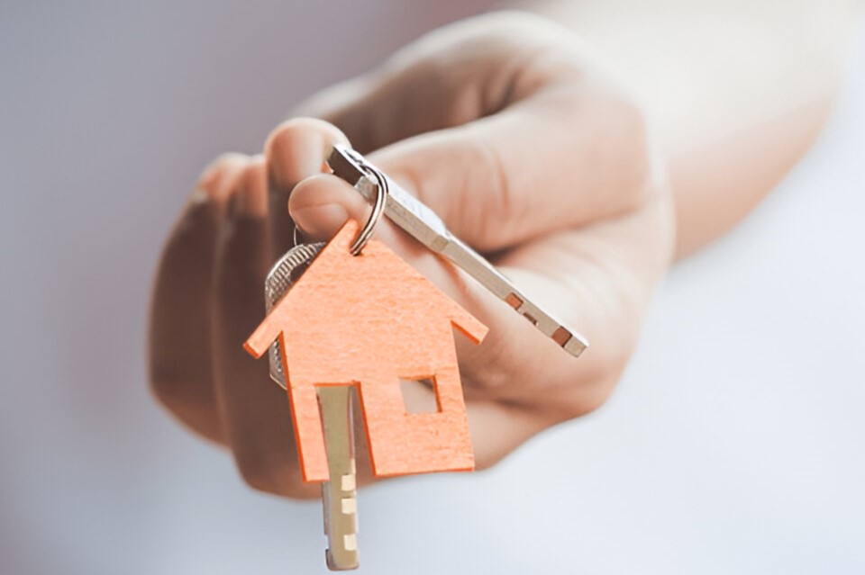 Hand holding house keys with orange keychain for lost key and device policy at Chelton Brown, Northamptonshire.