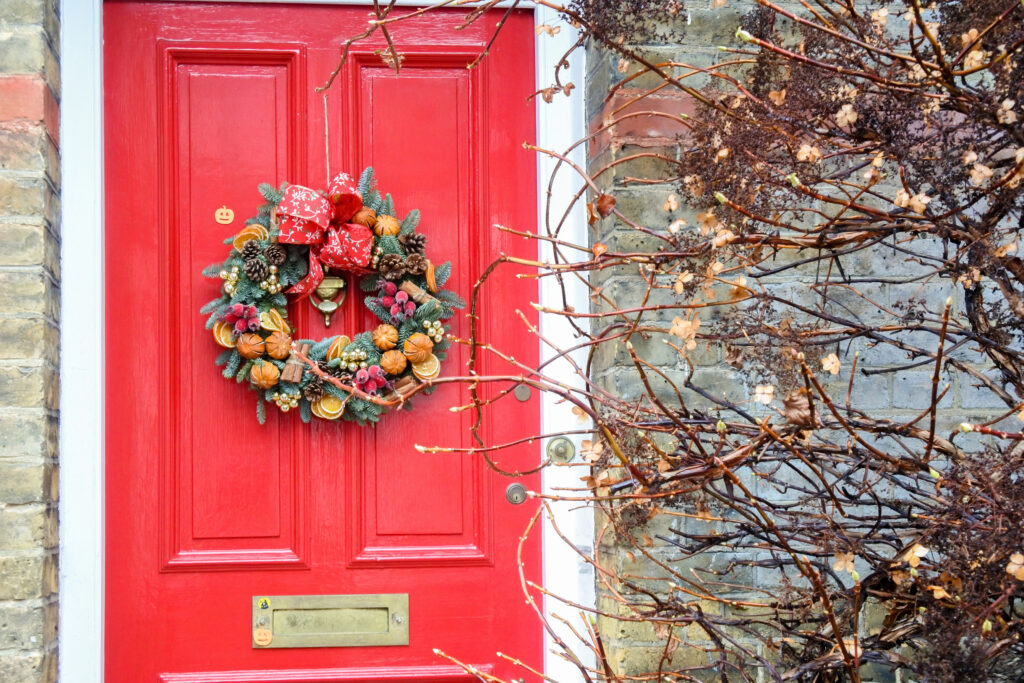 Red front door with Christmas wreath for selling your home in Northamptonshire with Chelton Brown estate agents.