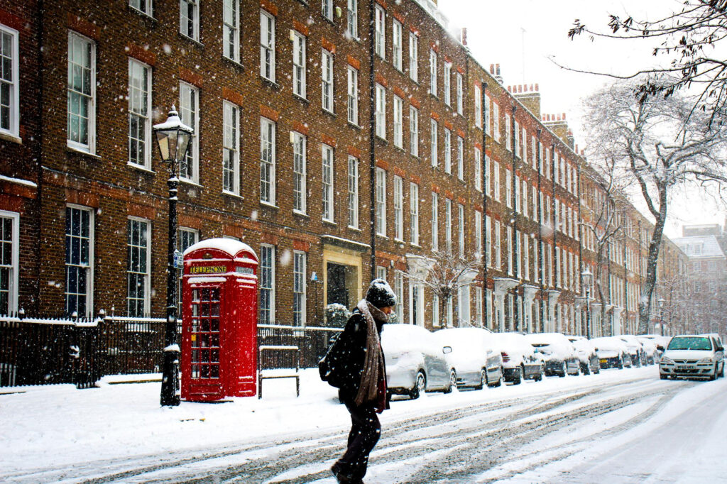 Snowy street scene with brick townhouses and red phone booth in Northamptonshire, marketed by Chelton Brown.